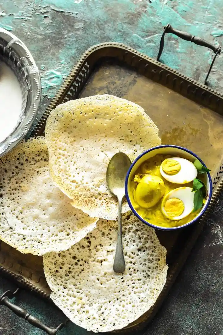 A traditional Kerala breakfast of soft appam served with egg curry, showcasing the rich flavors made complete with organic spices.