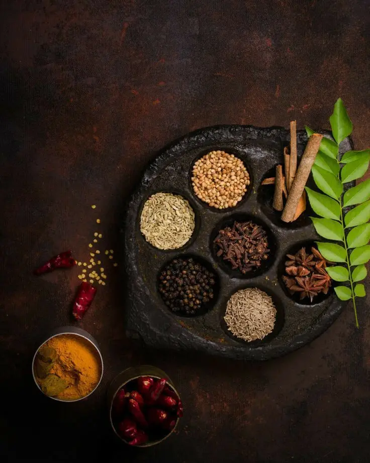 A vibrant mix of organic Kerala spices with fresh curry leaves, full of flavor and purity.